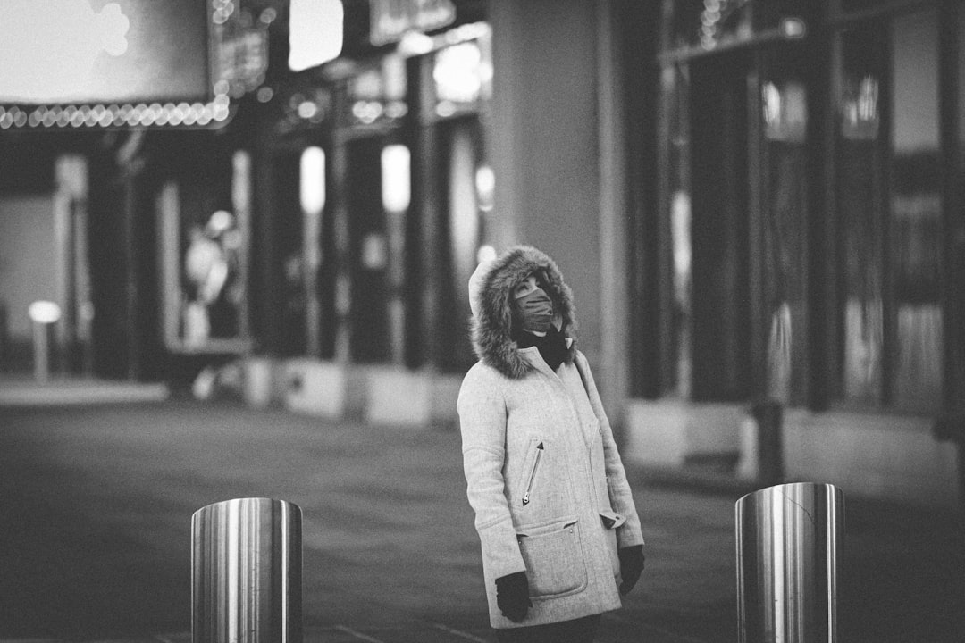 woman in white long sleeve shirt standing on sidewalk in grayscale photography