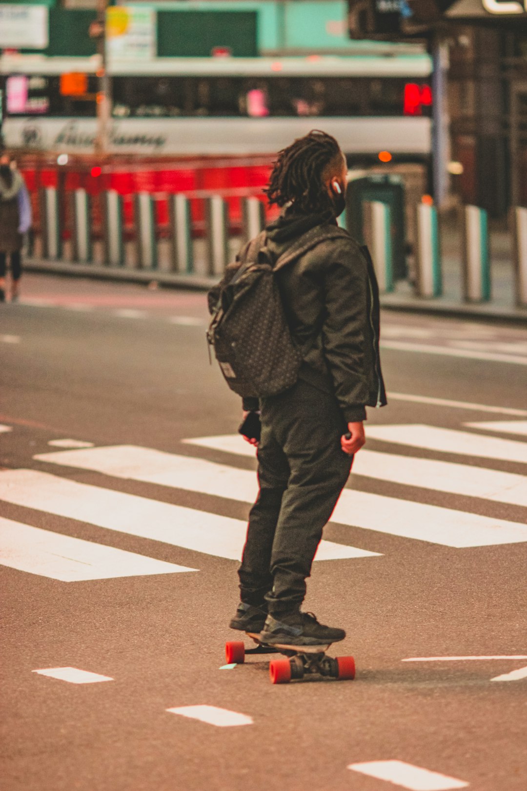 woman in black jacket and red pants walking on pedestrian lane during daytime