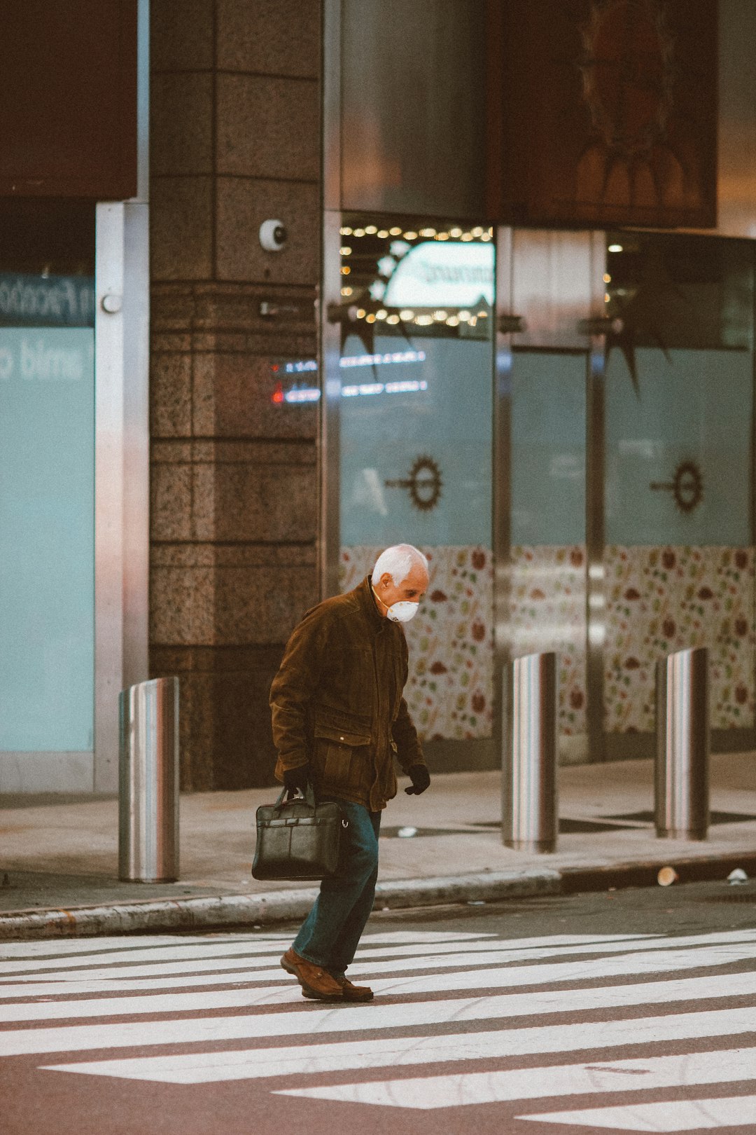 man in brown jacket and blue denim jeans walking on sidewalk during daytime