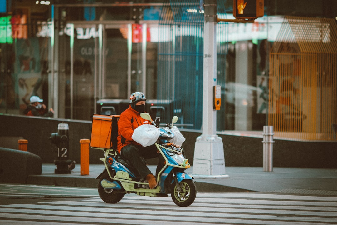 man in orange jacket riding on black and white motorcycle