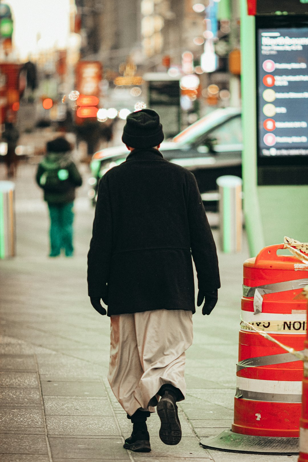 man in black hoodie and brown pants standing beside red and white box