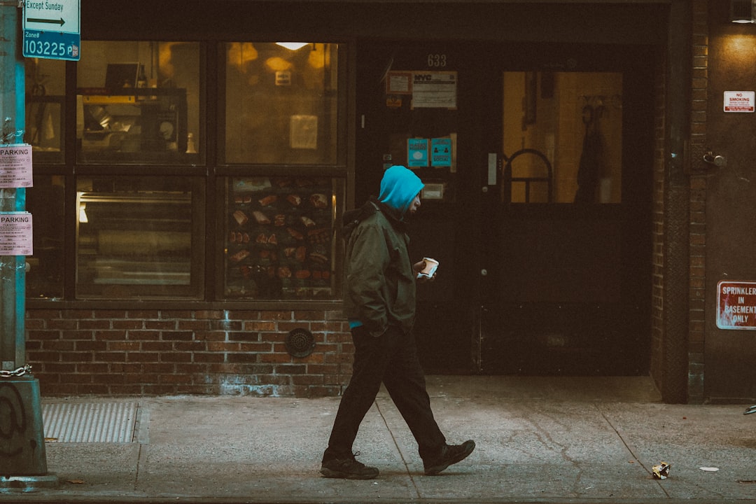 person in black jacket and gray pants walking on sidewalk during daytime