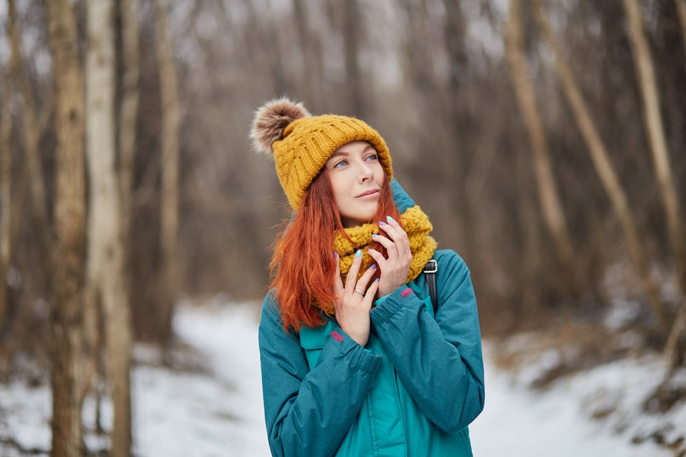 woman in blue jacket and brown knit cap standing on snow covered ground during daytime