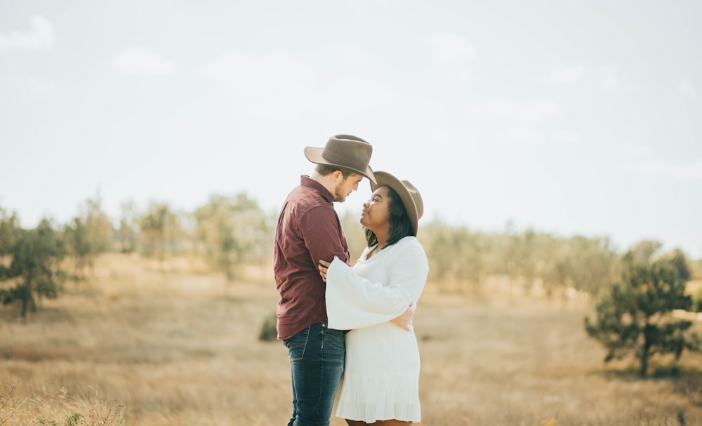 couple kissing on brown field during daytime