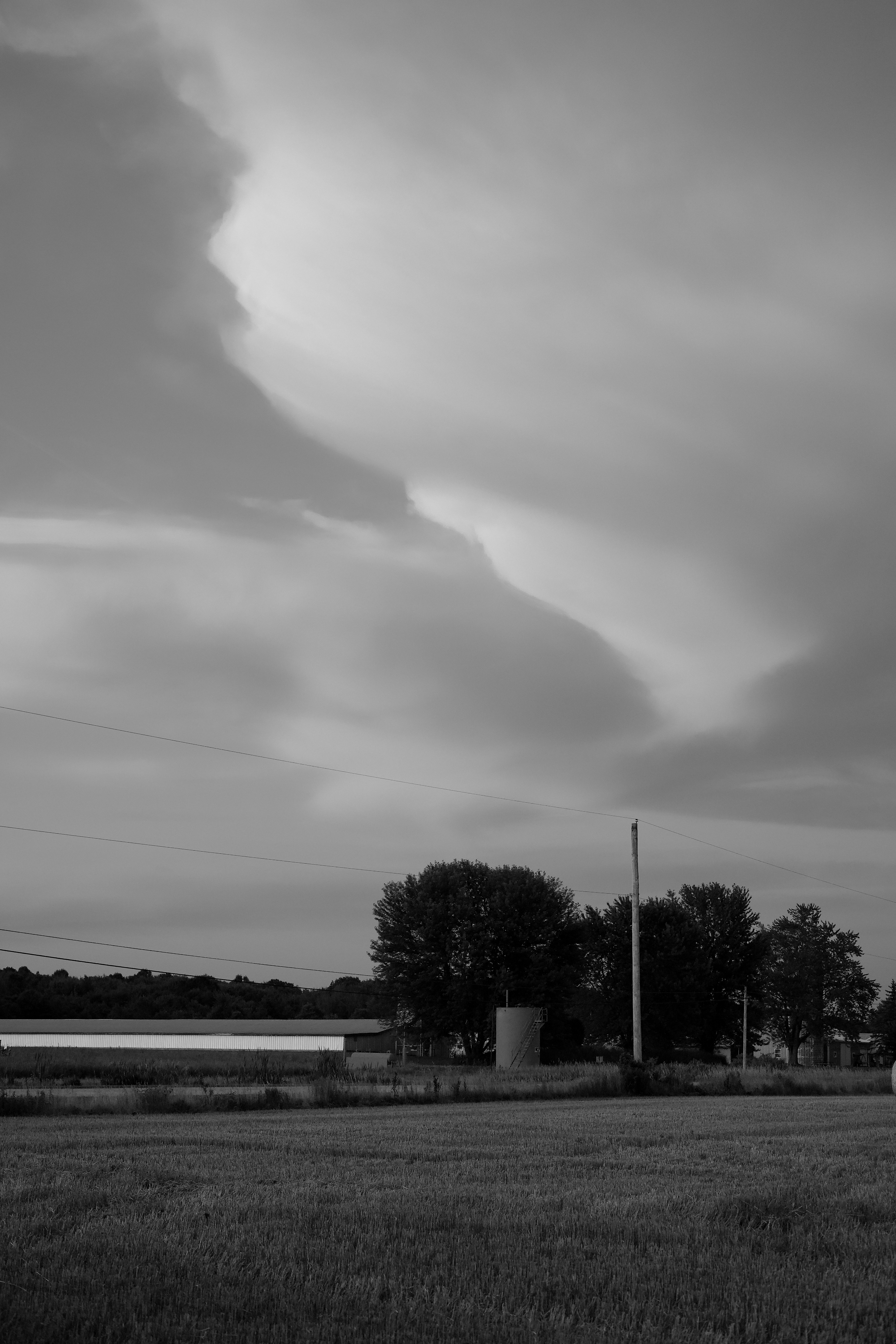 Sweeping rural Montana landscape with period farmhouse and dramatic storm clouds