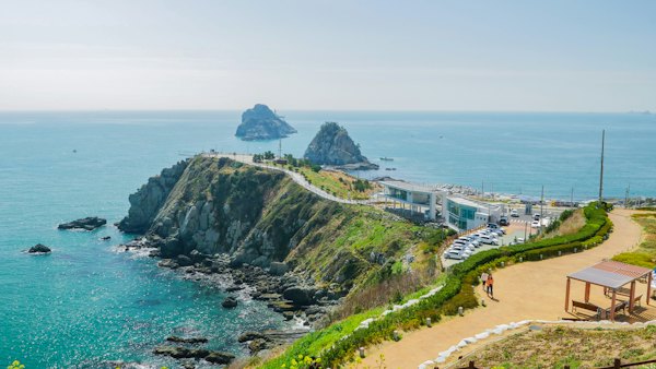 Green and brown mountain beside sea during daytime — Busan, South Korea