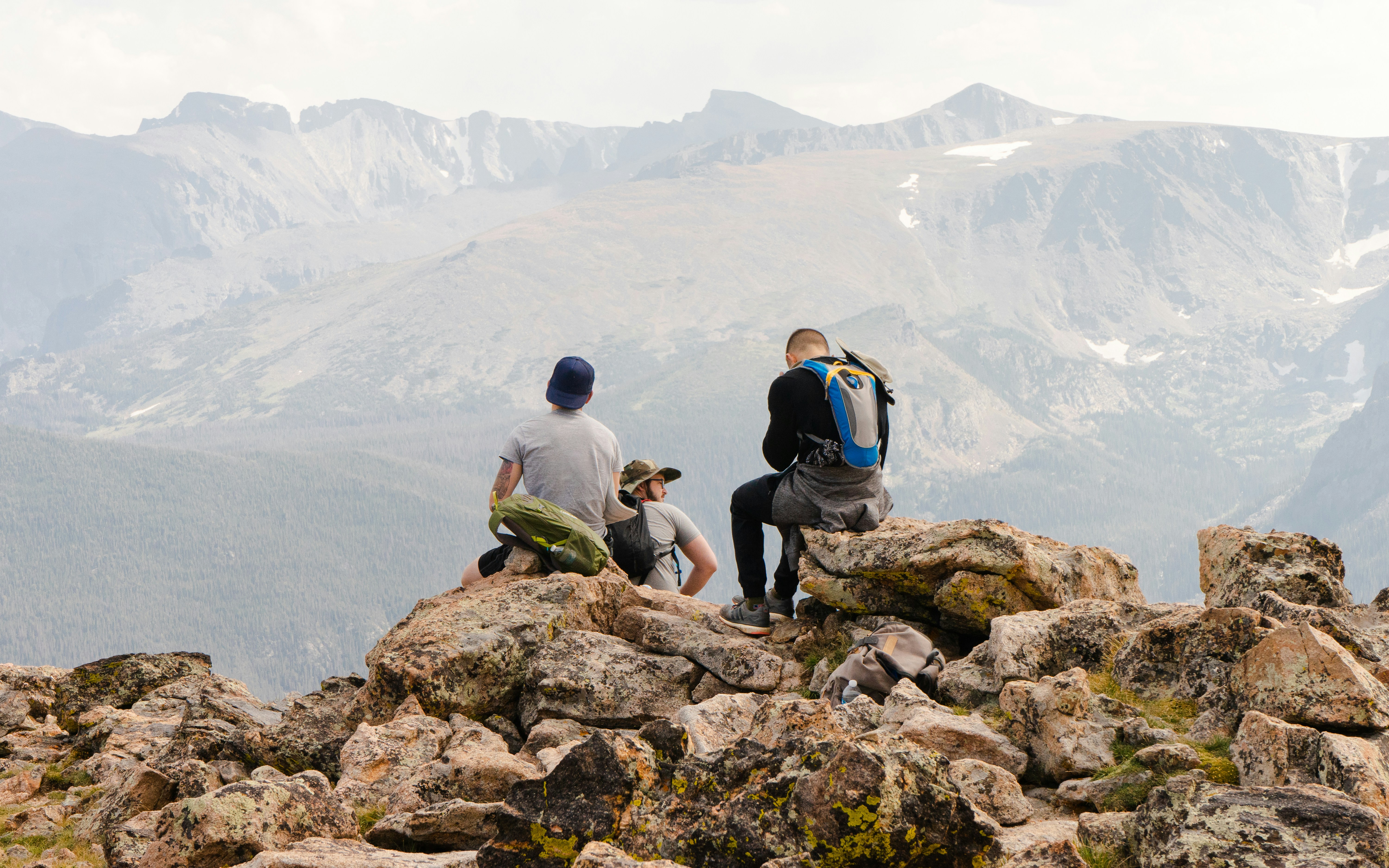 2 men sitting on rock formation near body of water during daytime, 