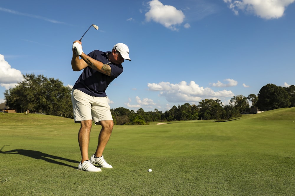 homme en chemise noire et short blanc jouant au golf pendant la journée