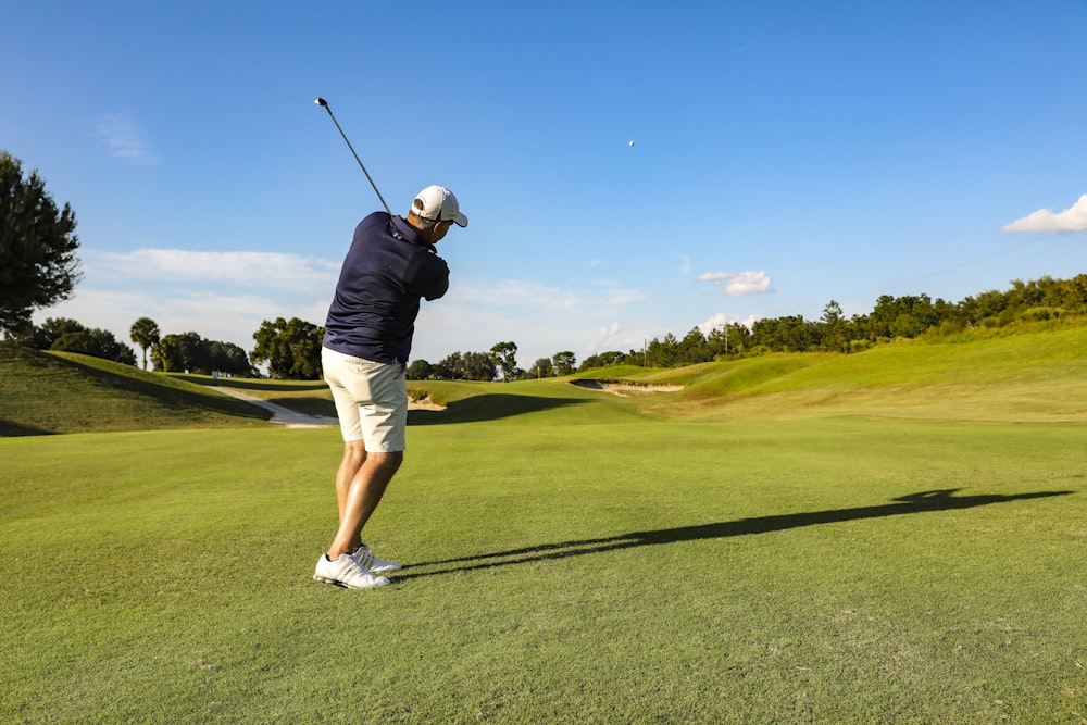 man in black t-shirt and white shorts playing golf during daytime