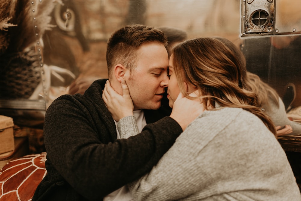 man in black long sleeve shirt kissing woman in white sweater