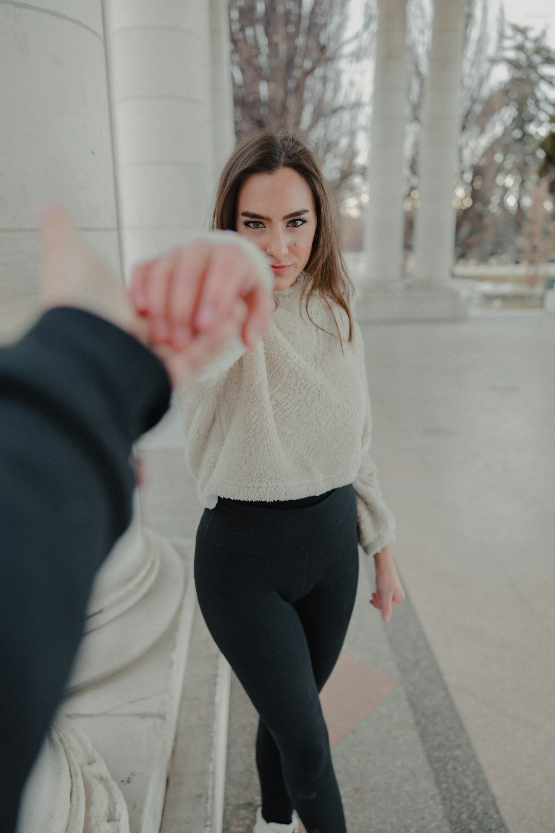 woman in white sweater and black pants sitting on white plastic chair