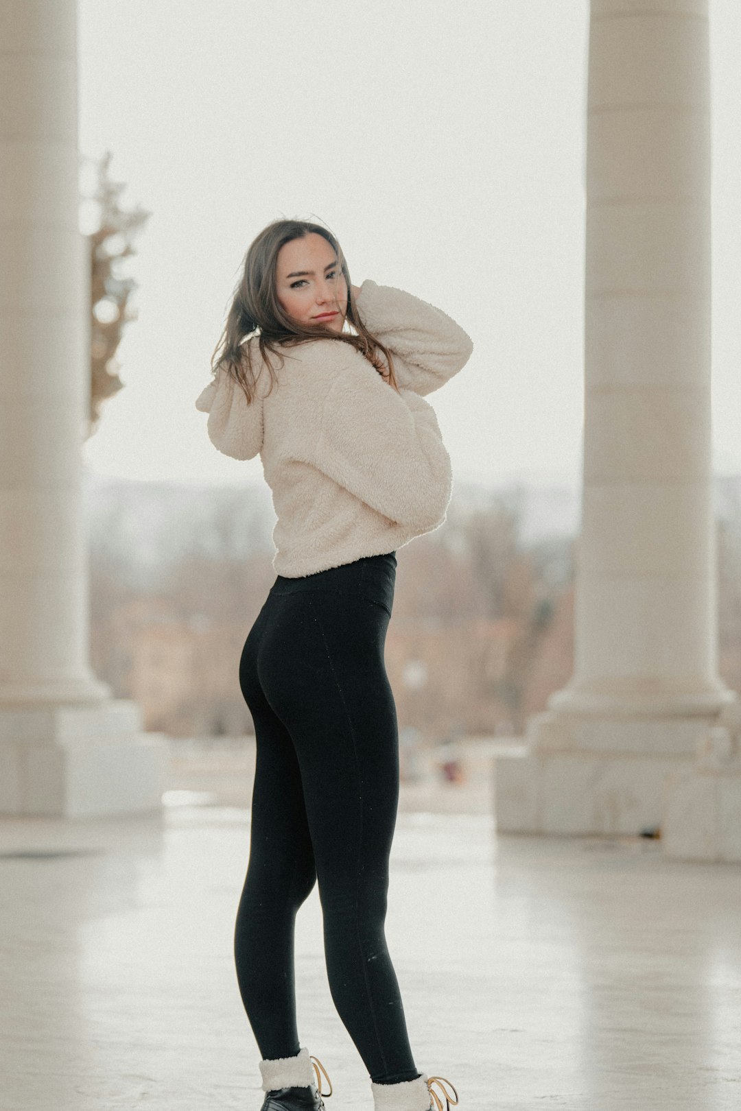 woman in white sweater and black leggings standing on white concrete floor during daytime