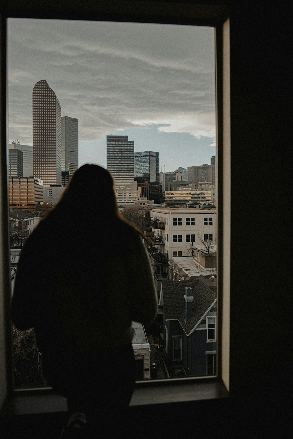 昼間、ビルの屋上に立つ黒いジャケットの女性