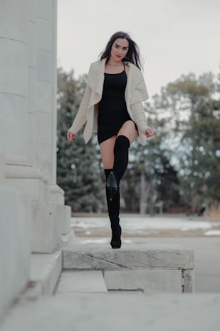 Woman walking confidently on a city street wearing stylish black boots from Solevogue.