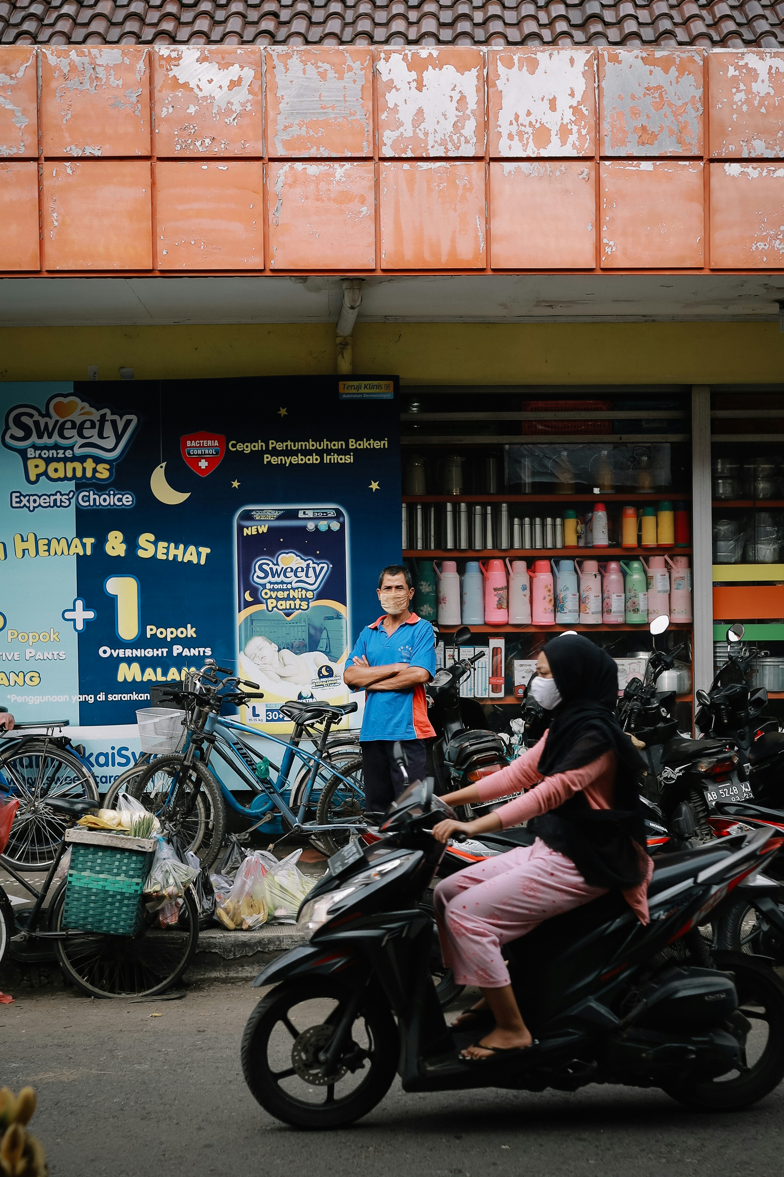 Wanita dengan kemeja lengan panjang merah muda mengendarai sepeda motor hitam