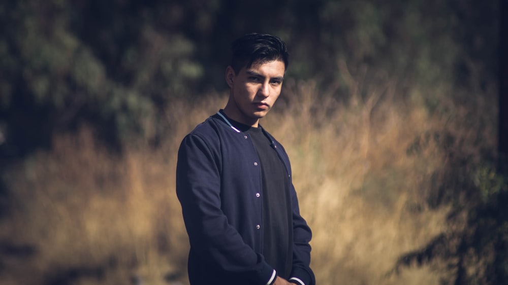 man in black jacket standing on grass field during daytime