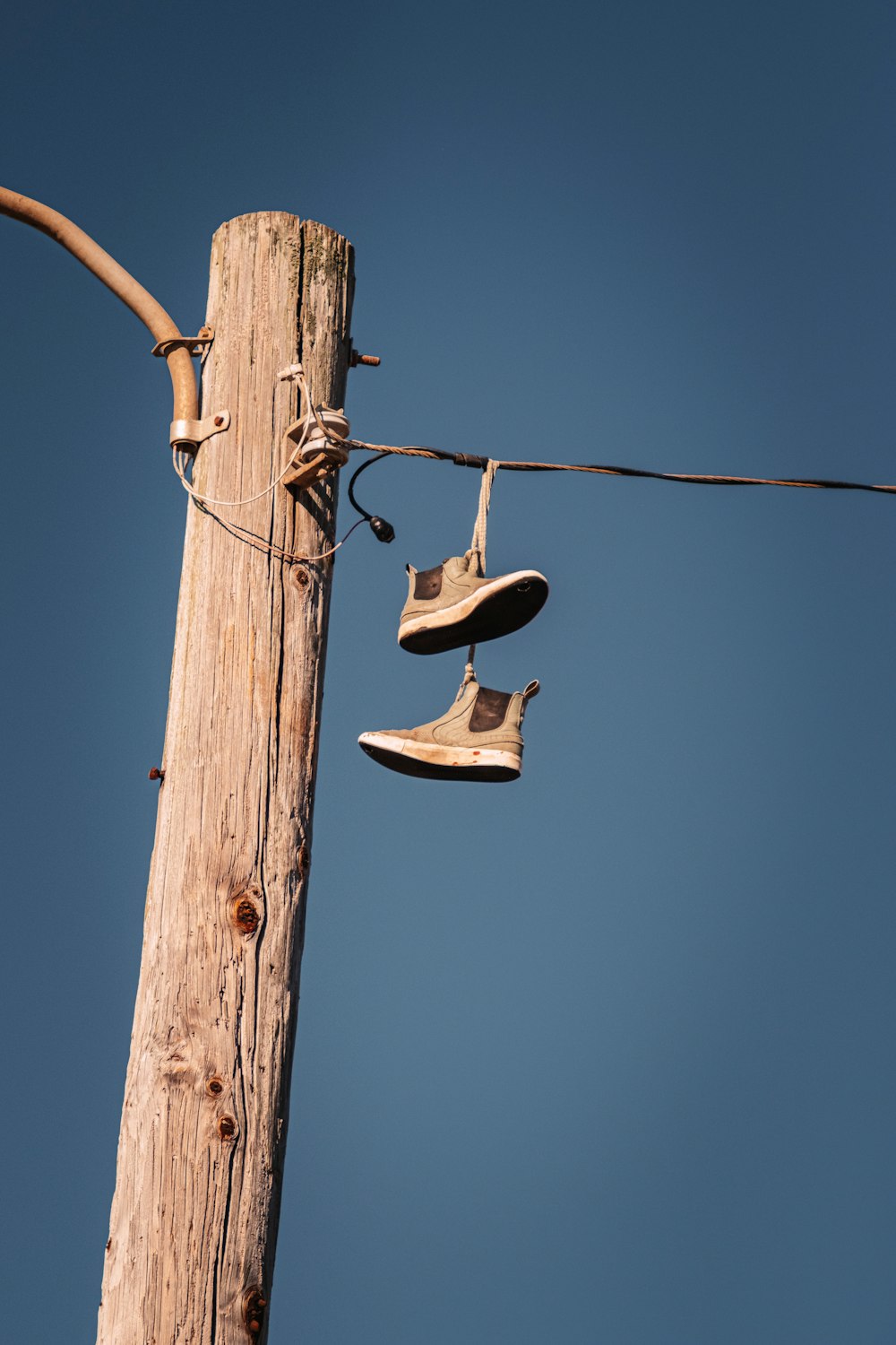 black and green boots hanging on brown wooden post