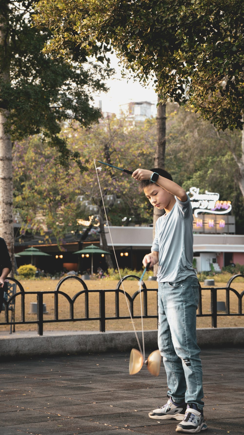 man in white crew neck t-shirt and blue denim jeans standing near black metal fence