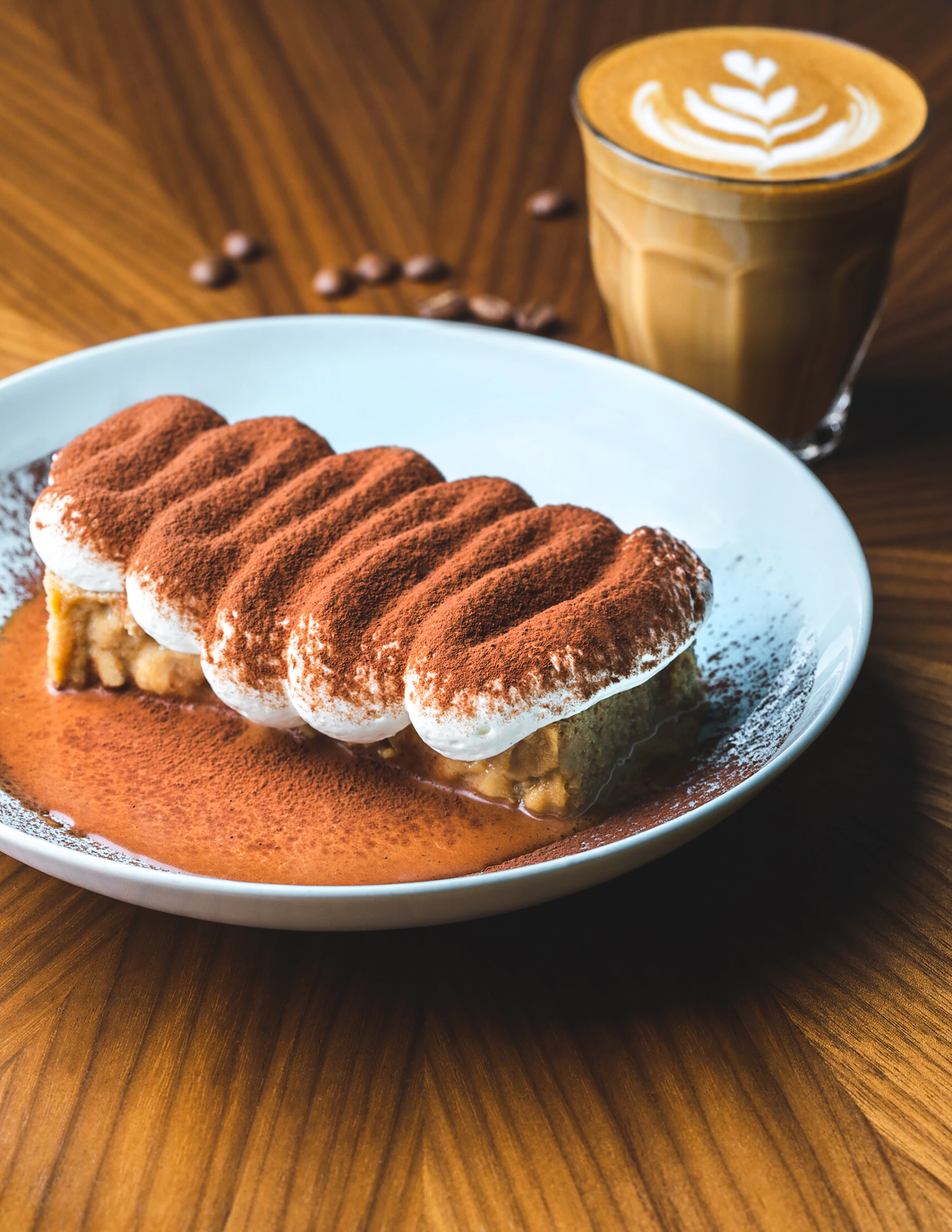 Tiramisù with piped mascarpone ridges dusted in cocoa on a white plate