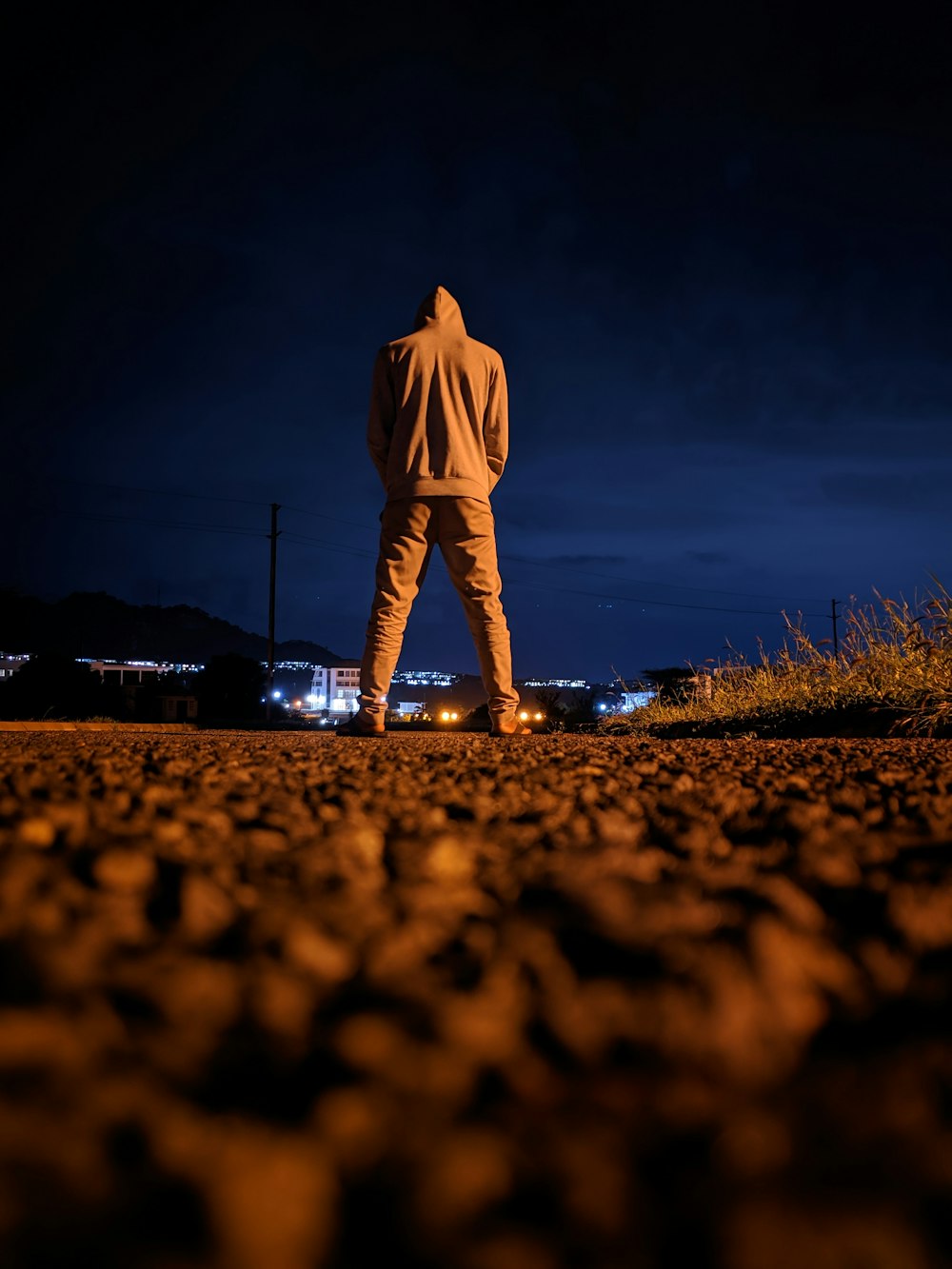 man in white long sleeve shirt and pants standing on brown field during night time