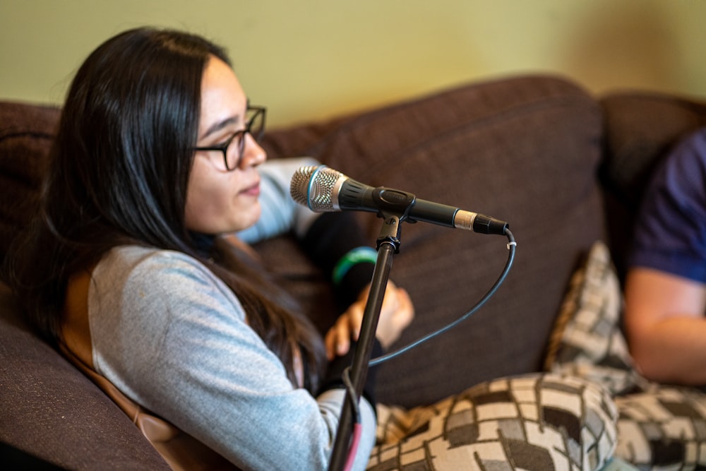 woman in gray long sleeve shirt sitting on brown and black sofa