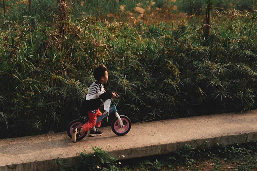 boy in black and white shirt riding on red and black trike