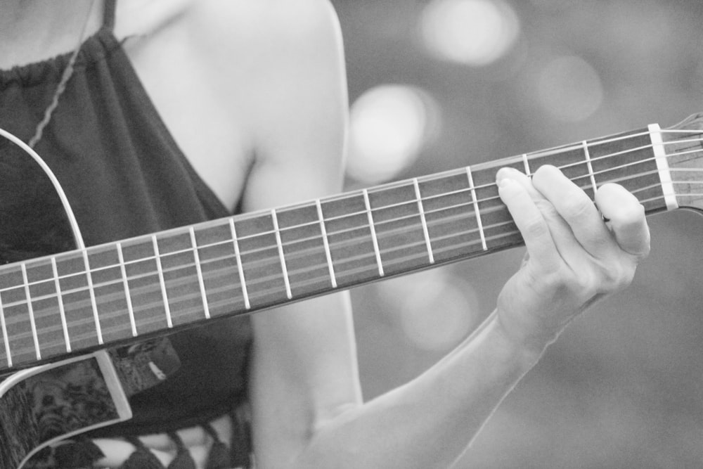 grayscale photo of woman playing acoustic guitar