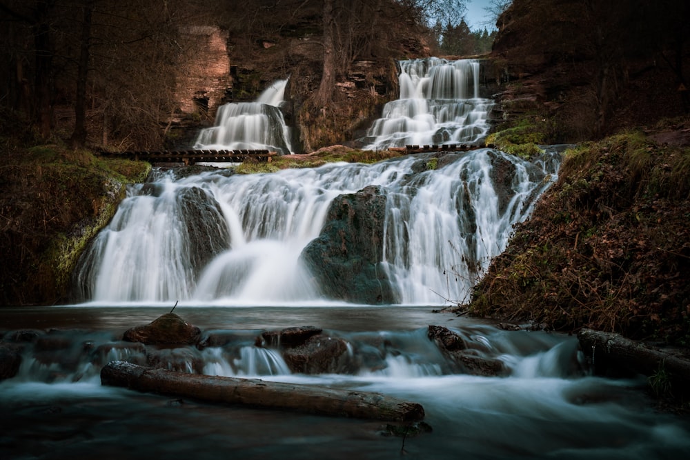 water falls in the middle of brown rocky mountain