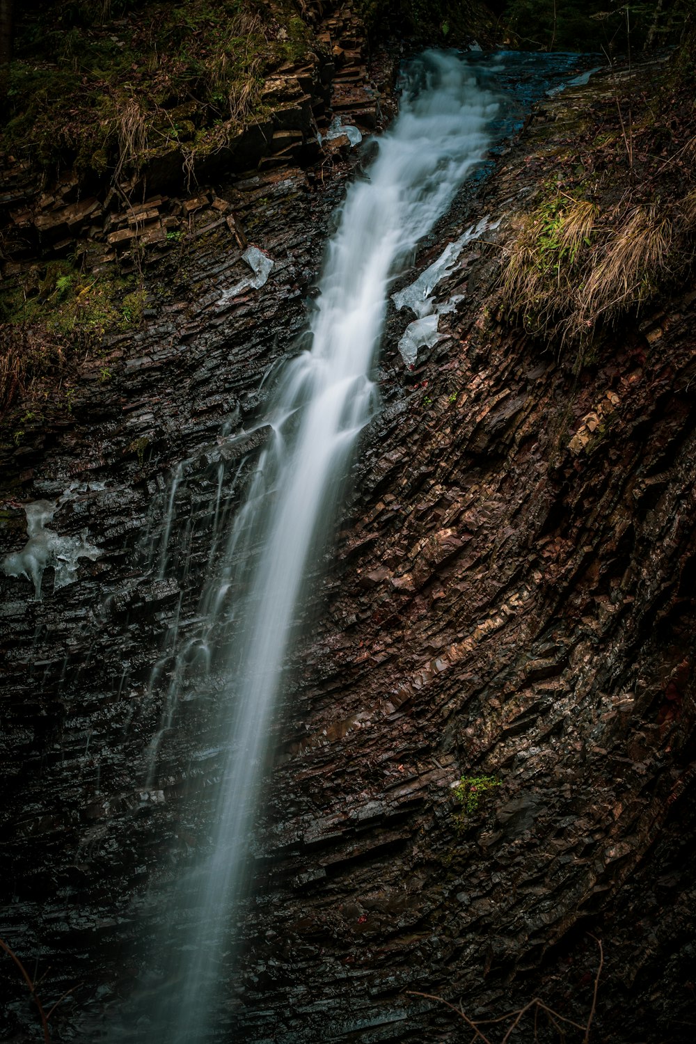 water falls on brown rocky mountain