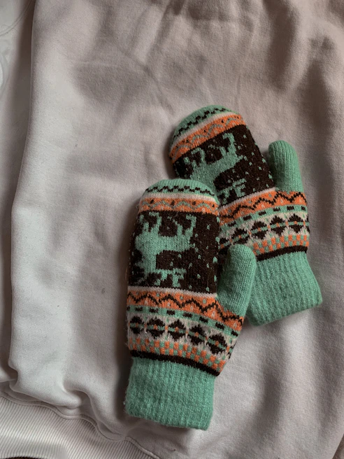Colorful winter gloves arranged neatly on a soft fabric background, showcasing vibrant patterns