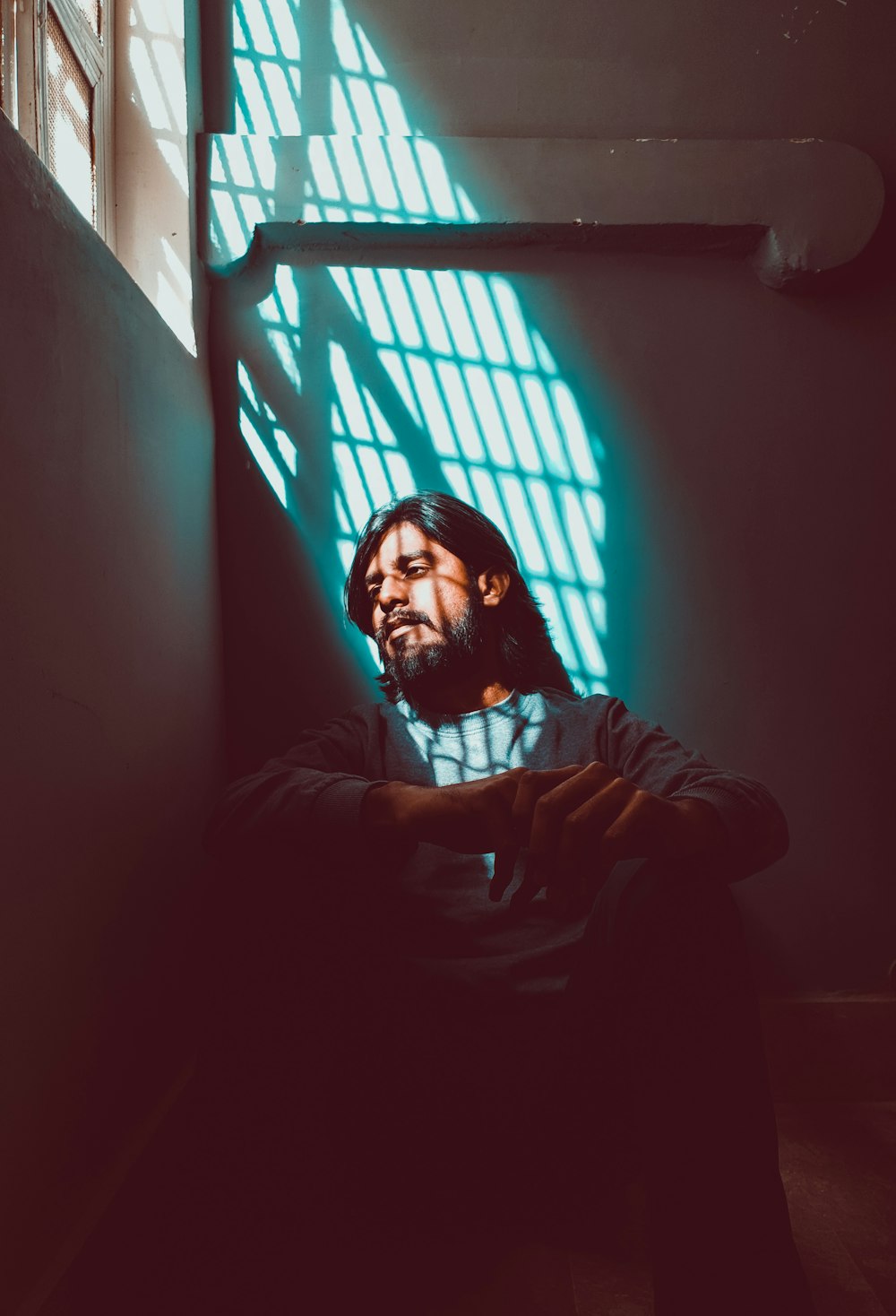 man in gray jacket sitting beside window