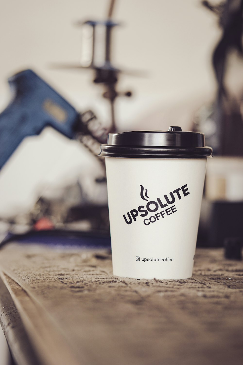 white and black disposable cup on brown wooden table