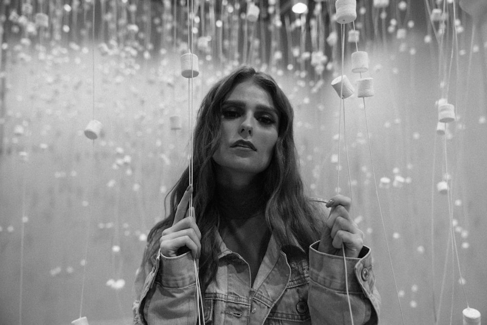 Photo en niveaux de gris d’une femme en chemise à carreaux tenant des guirlandes lumineuses