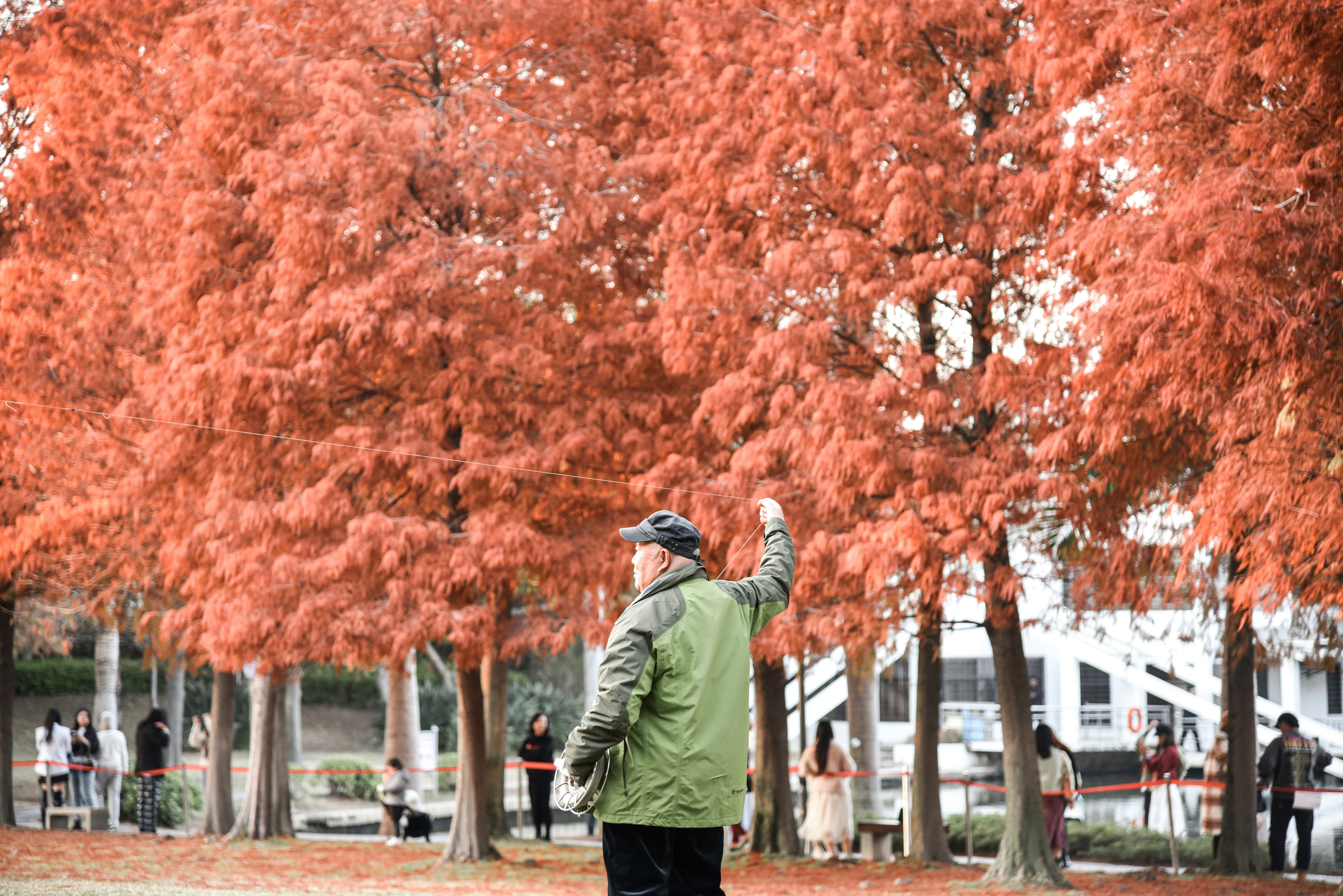 man in green jacket and black pants standing on sidewalk during daytime
