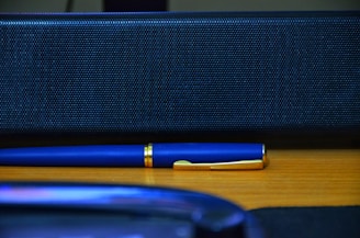 A sleek gold pen on a minimalist white marble desk beside a voice command device.