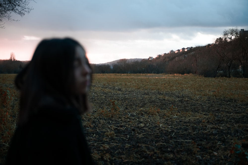 woman in black jacket standing on green grass field during daytime