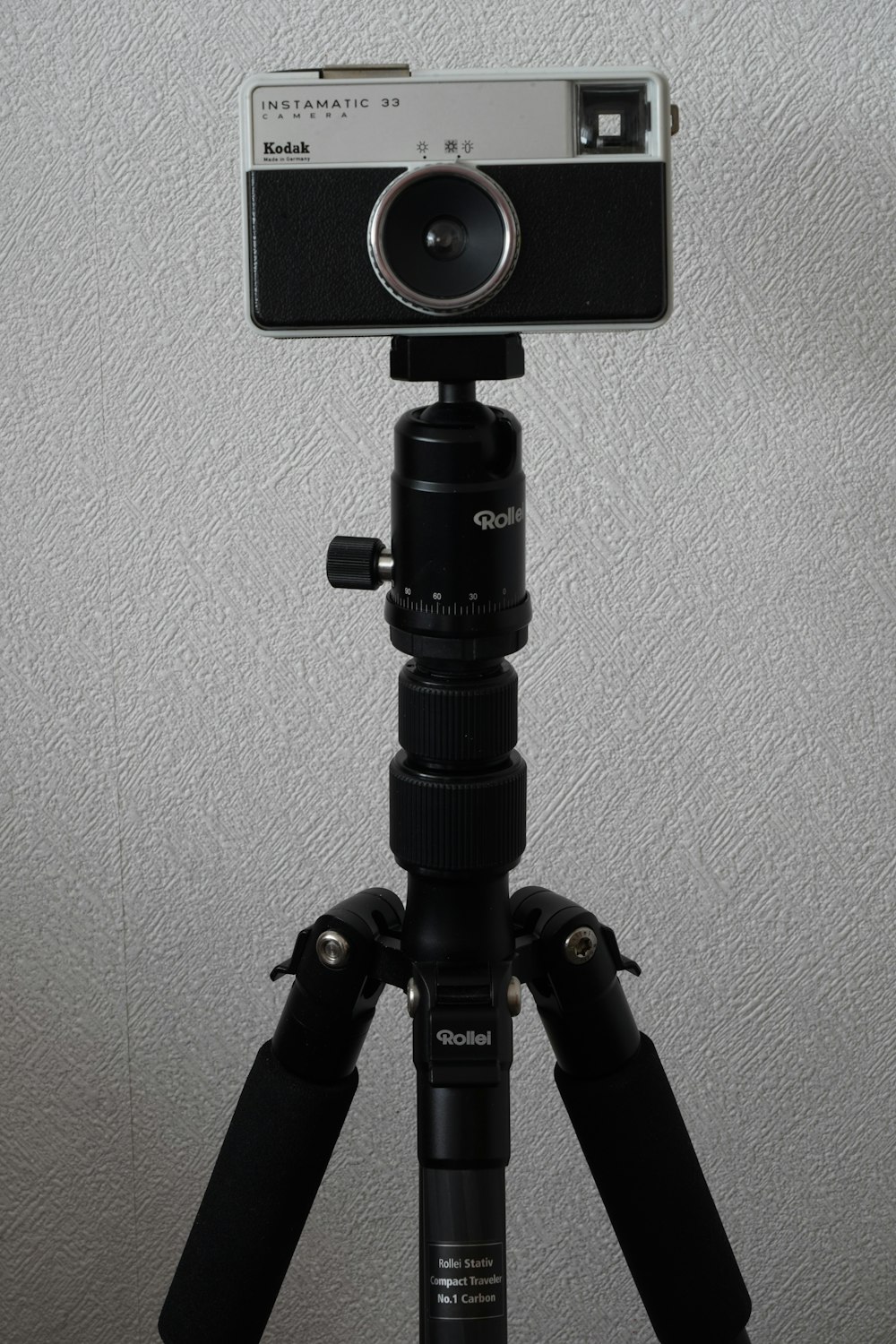 black camera tripod on white wall