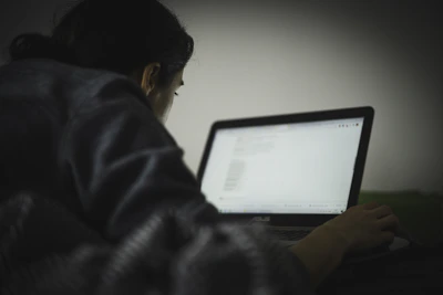 A cozy nighttime scene showing a person chatting anonymously on a laptop with soft lighting.