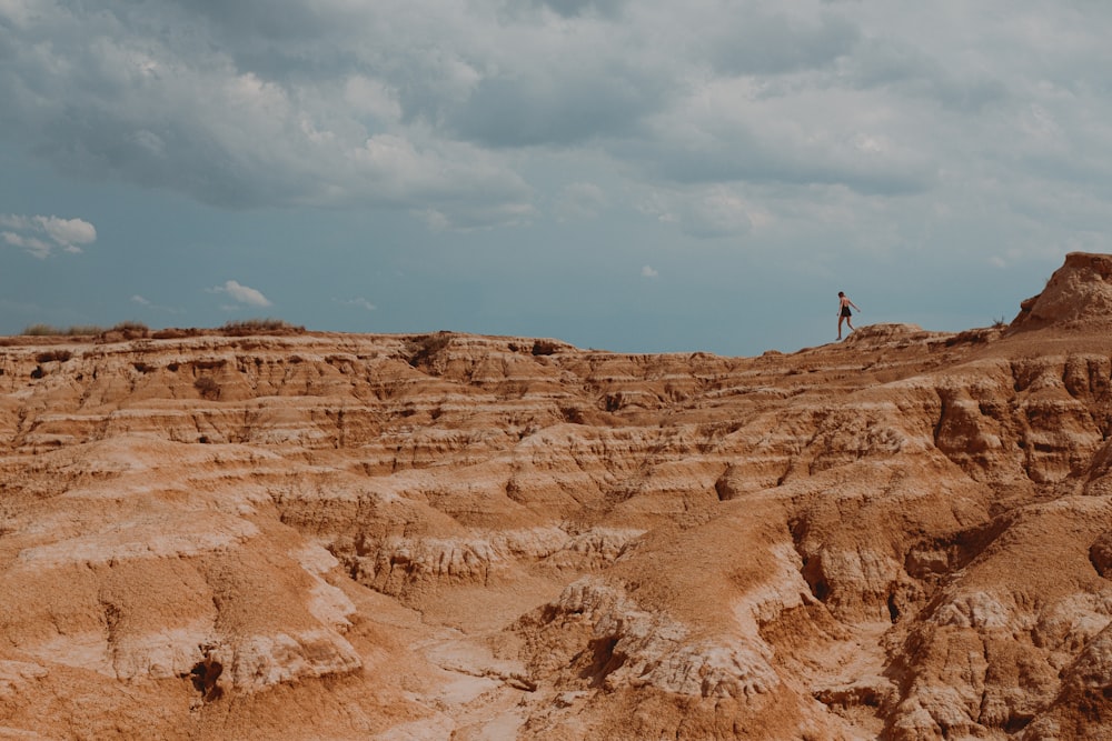 person standing on brown rock formation under blue sky during daytime