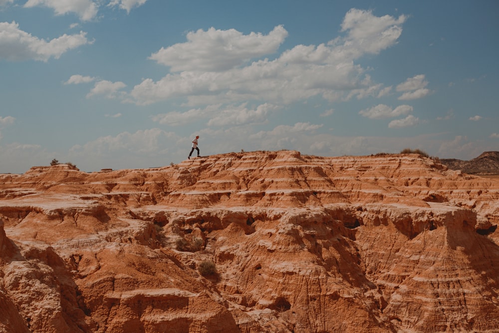 person standing on brown rock formation under blue sky during daytime