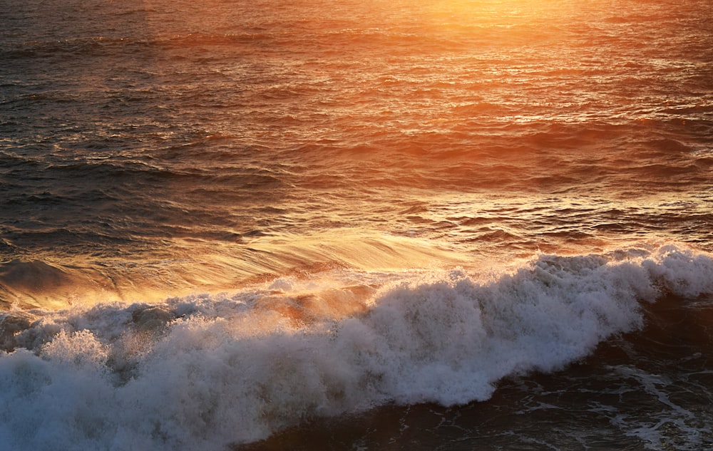 ocean waves crashing on shore during sunset