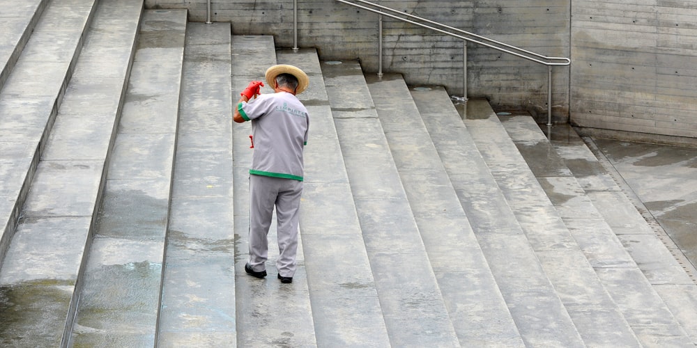 man in blue dress shirt and white pants standing on gray concrete stairs