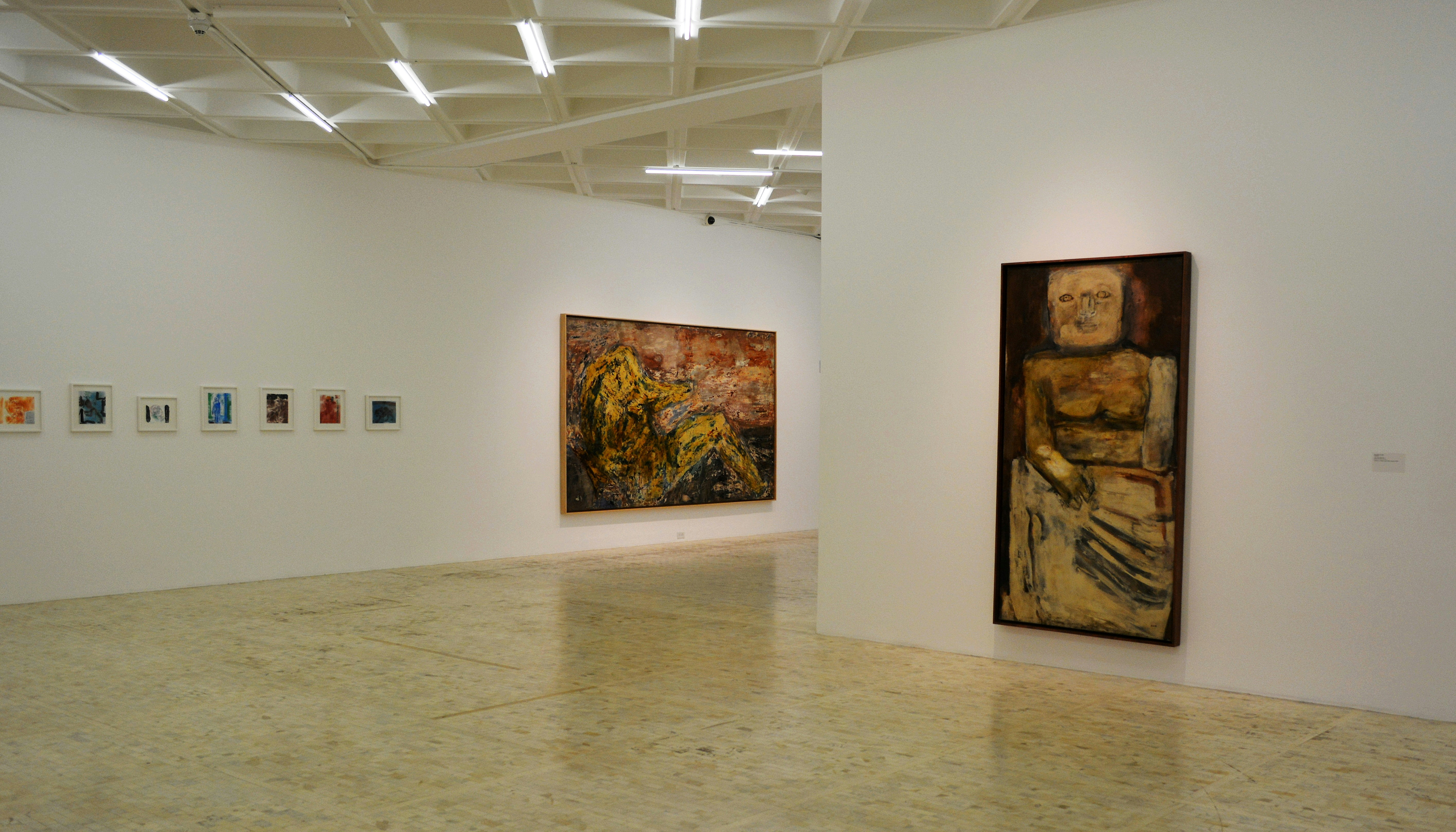 Interior view of a contemporary art gallery with minimalist white walls and vibrant artworks displayed.