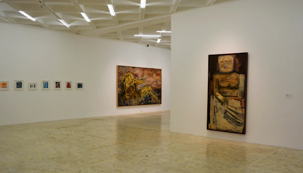 Interior view of a contemporary art gallery with minimalist white walls and vibrant artworks displayed.