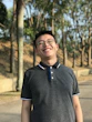 Photo of a cheerful man with glasses standing outdoors on a sunny day