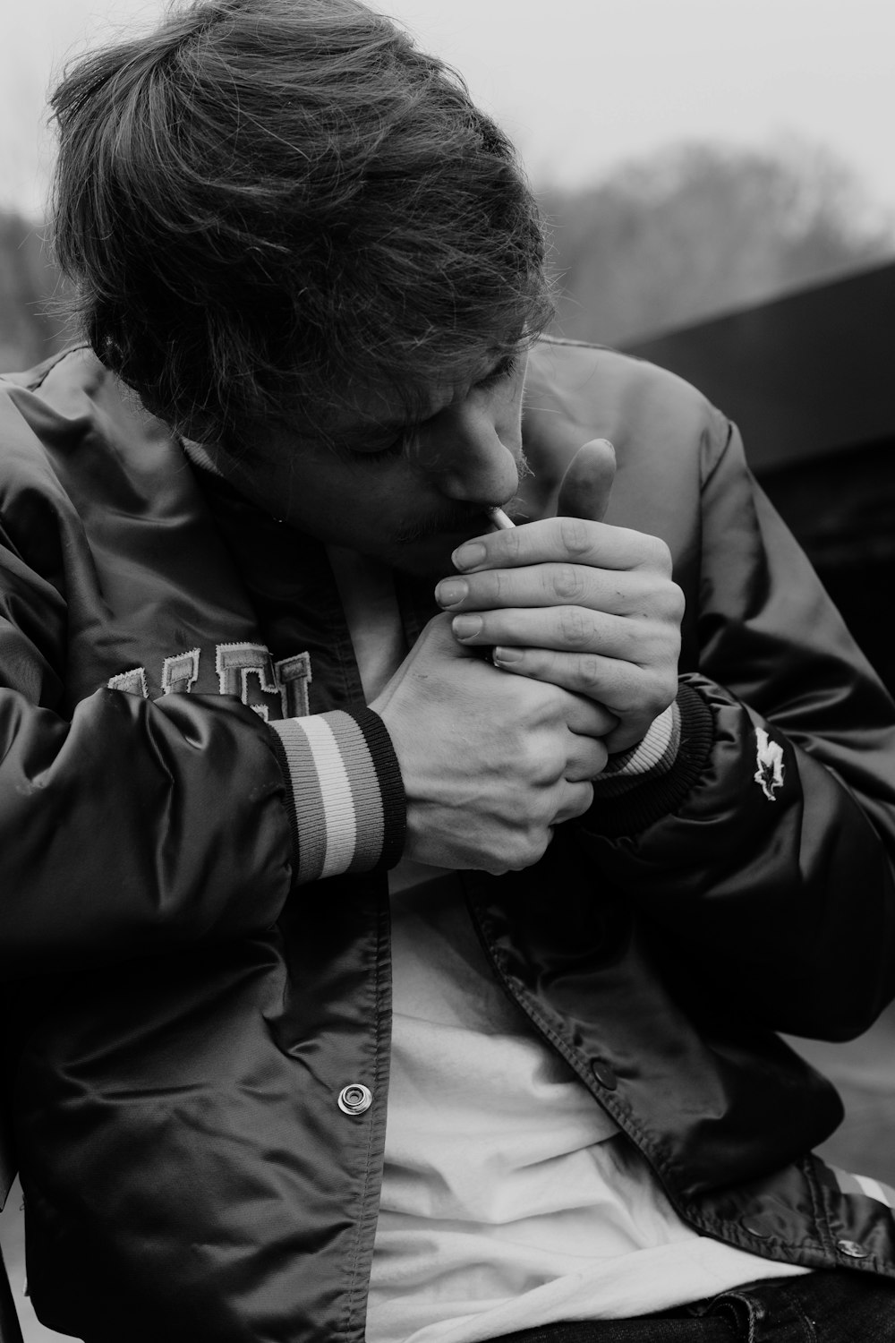 man in black jacket holding his face