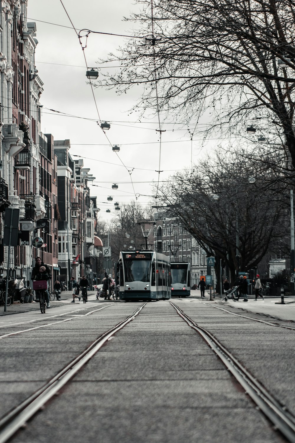 green tram on road between buildings during daytime