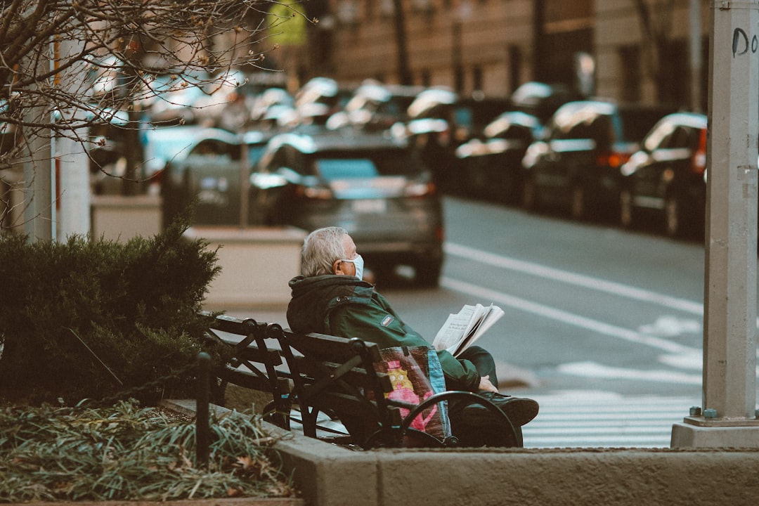 woman in black jacket sitting on bench in the street during daytime