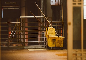 yellow plastic trash bin beside black metal stair railings