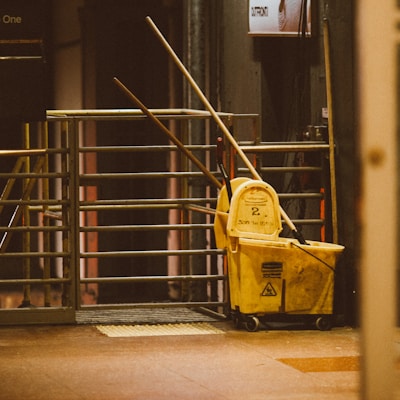 yellow plastic trash bin beside black metal stair railings